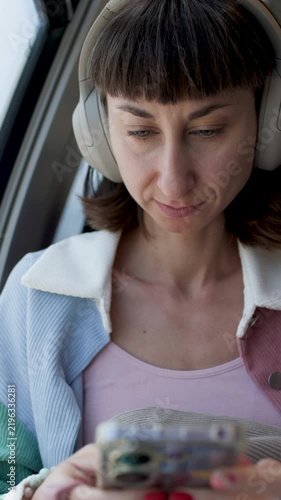 Woman in earphones travels by train. young woman wearing earphones and looking at her phone in the train. headphones and phone.  
