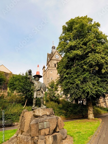 Statue with Traffic Cone on Head in Park with Clock Tower in Stirling, Scotland 