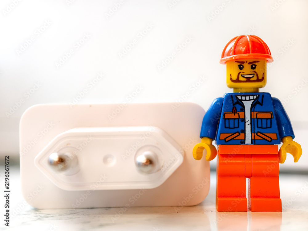 Fototapeta premium Russia, St. Petersburg, August 8, 2020 A small Lego man standing next to an electrical outlet