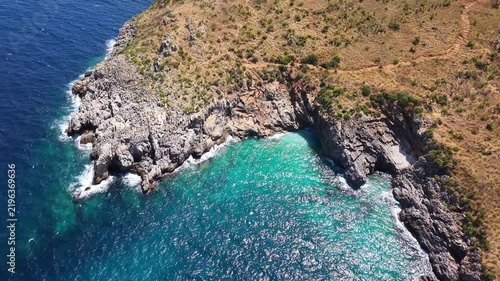 Aerial view of rocky coastline with turquoise waters and sandy hills, showcasing the natural beauty of the Mediterranean landscape during bright daylight. Sea resort at warm summer day