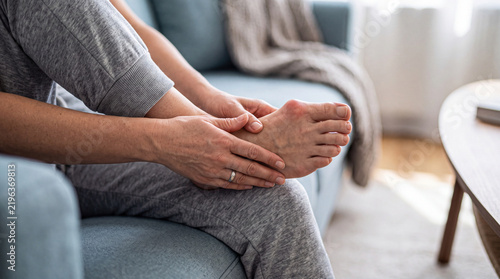 Woman suffering from severe foot pain holding her foot with a hallux valgus deformity and bunion for orthopedic and medical health concepts