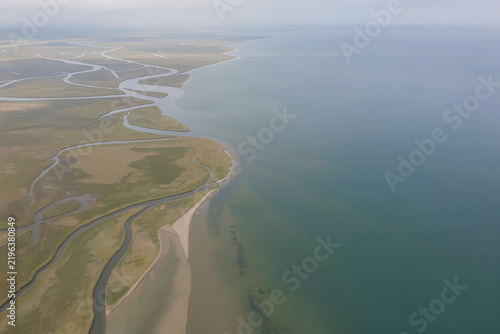 Aerial view of a broad river splitting into channels meeting a calm sea
