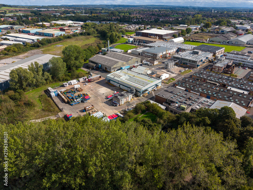 Aerial view of The Common featuring industrial warehouses, storage yards, and surrounding woodland in Stafford, England, United Kingdom.