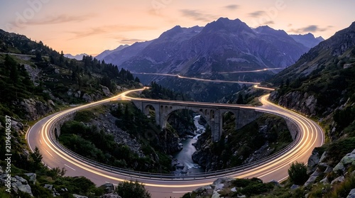 Mountain road winding through the valley with light trails from cars at dusk night drive long exposure mountain pass valley landscape