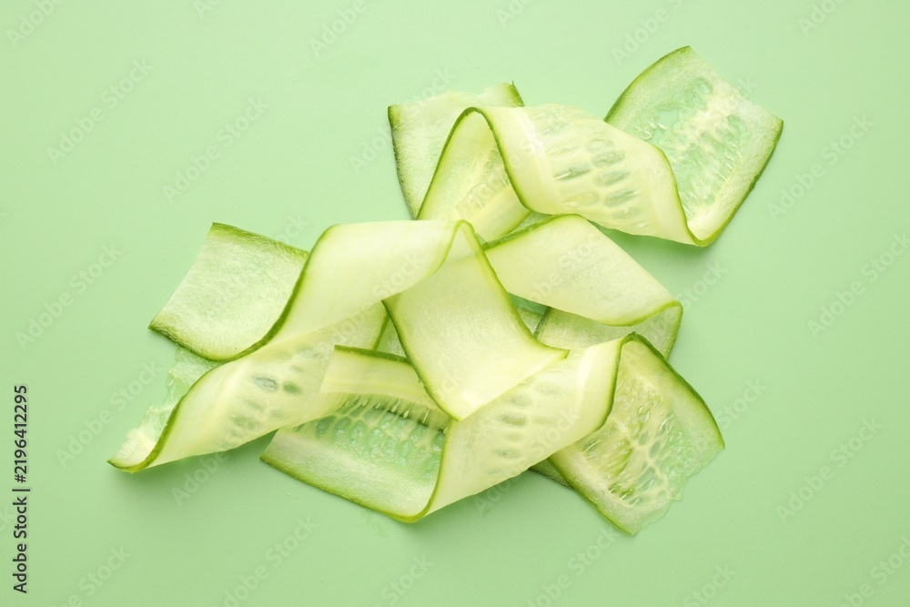 Fototapeta premium Slices of ripe cucumber on green background, flat lay