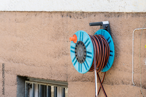 Photography Wall-mounted cable reel with electric cord hanging outside a building during day