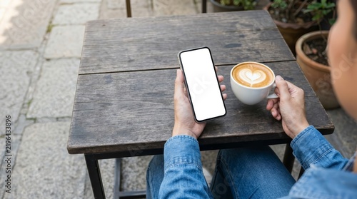 Blank mobile phone screen mockup held by a woman with coffee in an outdoor cafe setting
