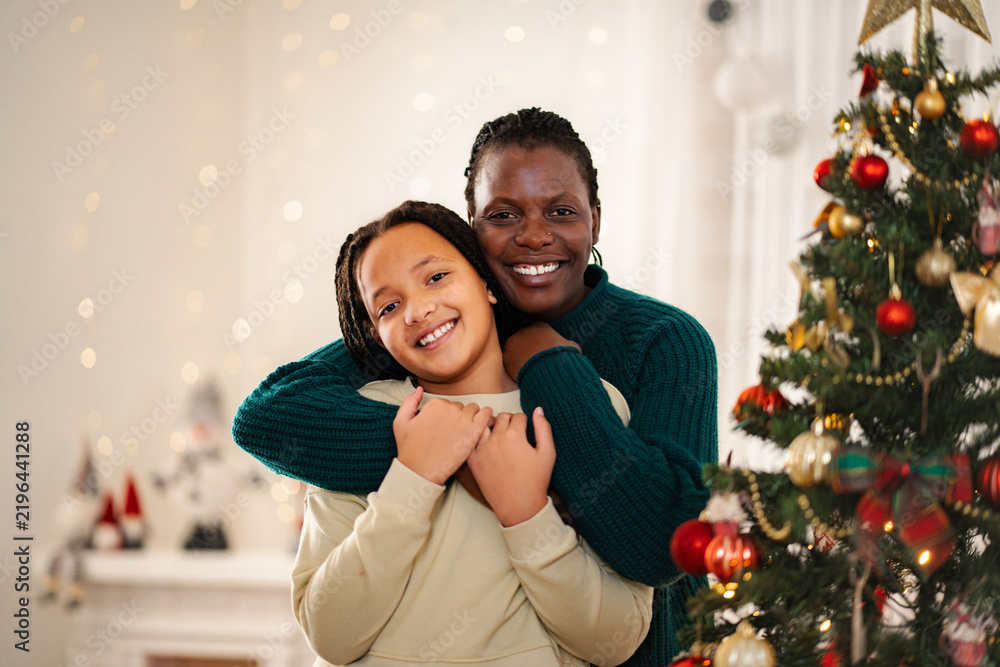 Fototapeta premium Afro American mother and daughter hugging smiling during Christmas holidays
