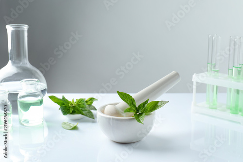 Konstfotografi Mortar with pestle, fresh basil leaves and glassware on white table