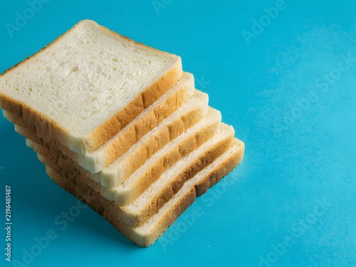 Stack of white sliced bread with clean edges displayed on bright blue studio background