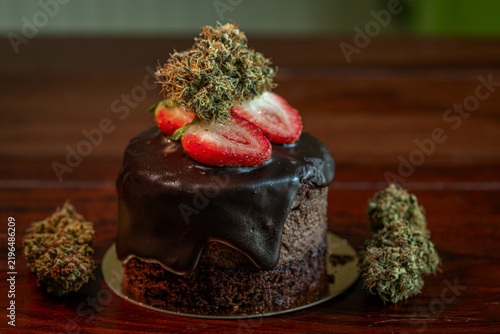 Chocolate strawberry fruit brown cake wooden table with marijuana flower blooms