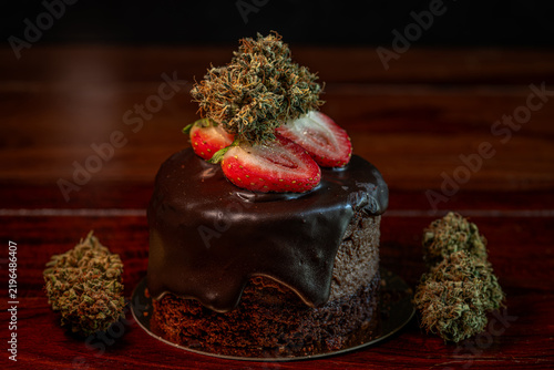 Chocolate strawberry fruit brown cake wooden table with marijuana flower blooms