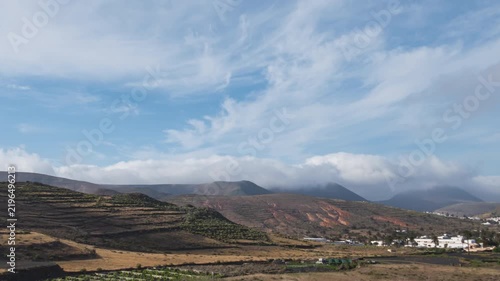 Hyper lapse of running clouds over Famara mountainous massif and Haria town in the north of the island of Lanzarote, Canary Islands, Spain