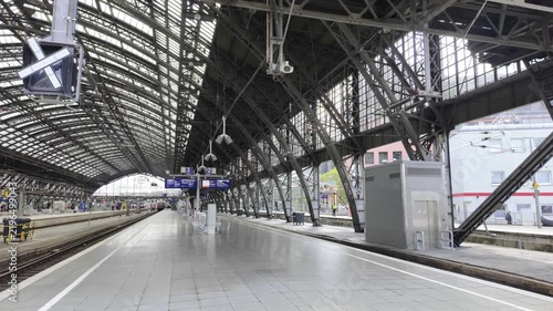 Outdoor view of railway tracks, overhead power lines, signals, and platforms under a cloudy sky at Cologne Central Station, Germany.