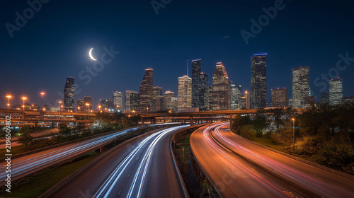 Futuristic Cityscape at Night with Crescent Moon and Curved Highway Light Trails