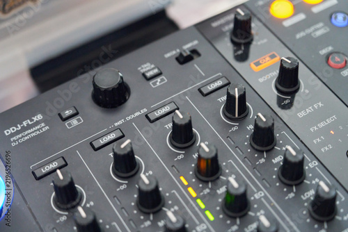 Close-up of DJ audio mixer console with illuminated knobs, faders, and control buttons for beat mixing