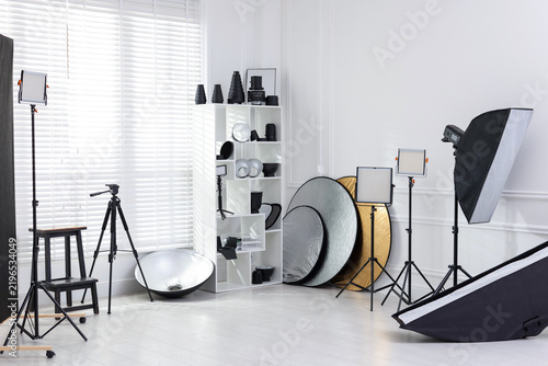 Different modern lighting equipment and tripod in photo studio