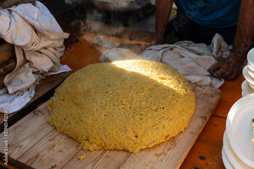 Fotografía a form of hot, steaming polenta just poured onto a wooden cutting board, typical of Italian gastronomic tradition