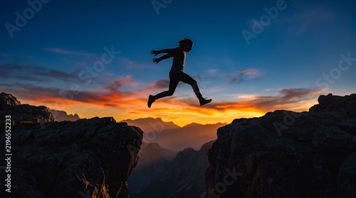 Close-up silhouette of a man jumping across a gap in a cliff, captured with a long lens and compressed perspective.