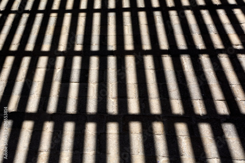 Geometric play of light and shadow creating a rhythmic striped visual effect on outdoor masonry paving.