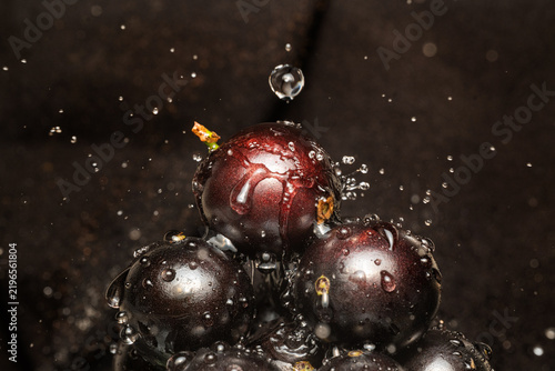 Water droplets on jabuticaba fruit; water droplets falling onto some jabuticabas and creating beautiful shapes; selective focus.