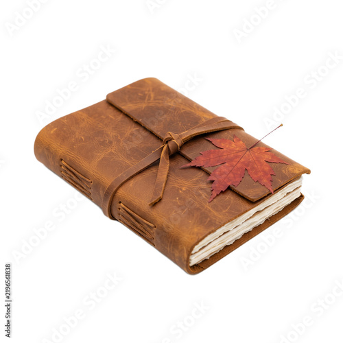 A closed leather journal with a red maple leaf on top isolated on white background with string decorated single brown leather notebook notebook tied