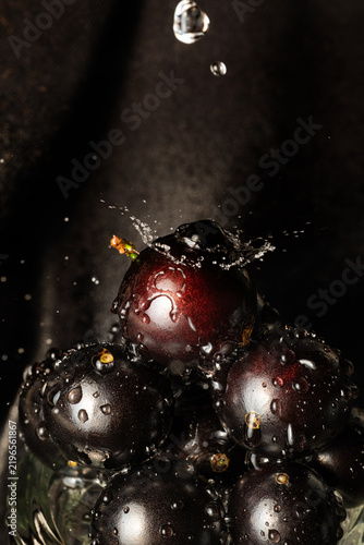 Water droplets on jabuticaba fruit; water droplets falling onto some jabuticabas and creating beautiful shapes; selective focus.