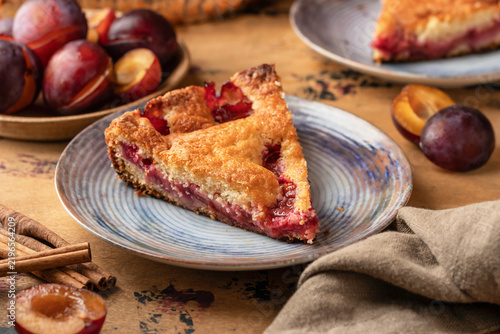 Homemade New York Times plum cake. Slice of autumn fruit pie in a plate on wooden background. Home cooking, recipe