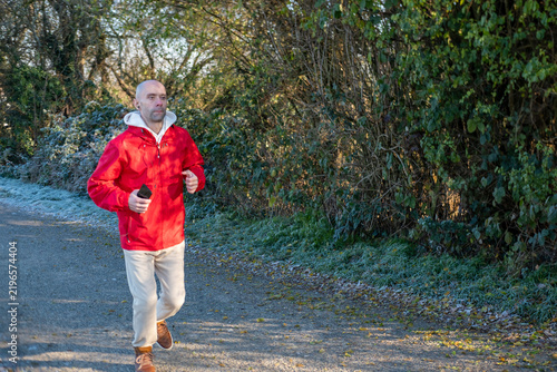 Bild auf Leinwand young man in red jacket running on frosty morning, solo training, active lifesty