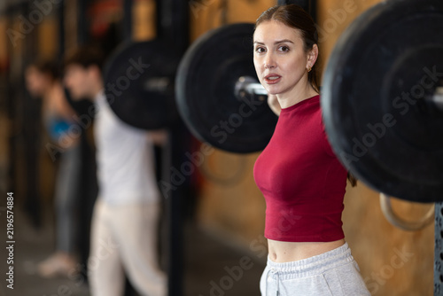 фотографія Active athlete young woman during exercises to strengthen muscles of back and body using barbell and extra weight