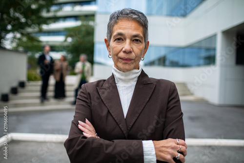 Confident senior businesswoman with arms crossed outside office