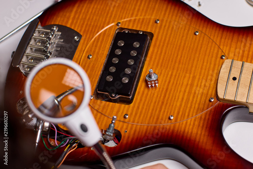 Obraz na płótnie Close up of technician hands repairing electric guitar control cavity under magn