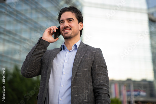 Confident businessman talking on mobile phone in city
