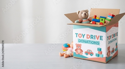 Toy drive donations box with stuffed bear and toys on table  