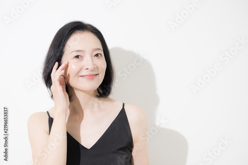 Quadro su tela A middle-aged Japanese woman smiling as she touches her eyes; an anti-aging imag