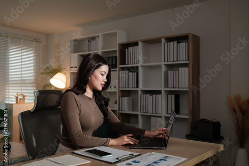 Young woman working on laptop in home office at night
