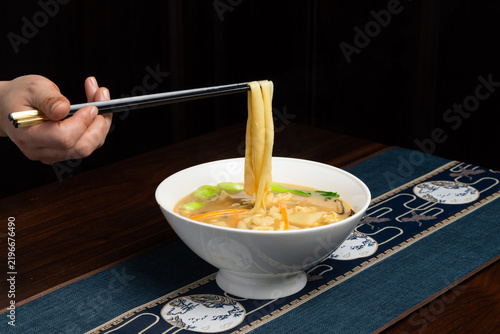 Chopsticks Lifting Egg Noodles. Chinese Noodle Soup Action Shot Close-up