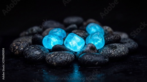Glowing blue stones arranged carefully among smooth black river pebbles creating a striking contrast in the dark.