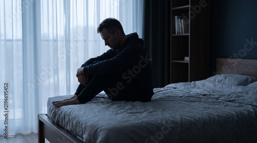 Man Sitting Alone in Shadowed Bedroom Symbolizing Loneliness Emotional Isolation Stress and Need for Support