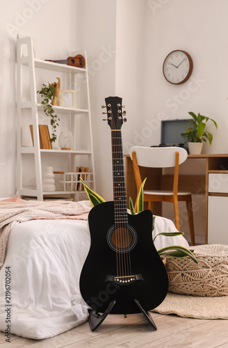 Interior of light bedroom with guitars, workplace and plants