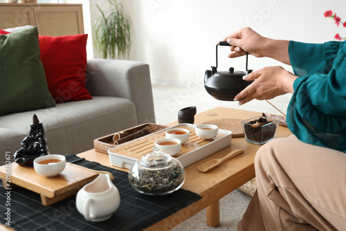 Woman with black tea set on table at home