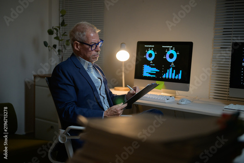 Senior businessman analyzing financial data working late at night