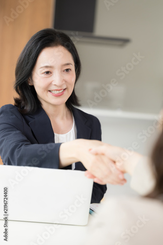 Plakat 笑顔で握手をする日本人ミドル女性、商談や契約で相手と信頼関係を築く50代女性ビジネスパーソン