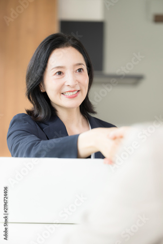 Plakat 笑顔で握手をする日本人ミドル女性、商談や契約で相手と信頼関係を築く50代女性ビジネスパーソン縦
