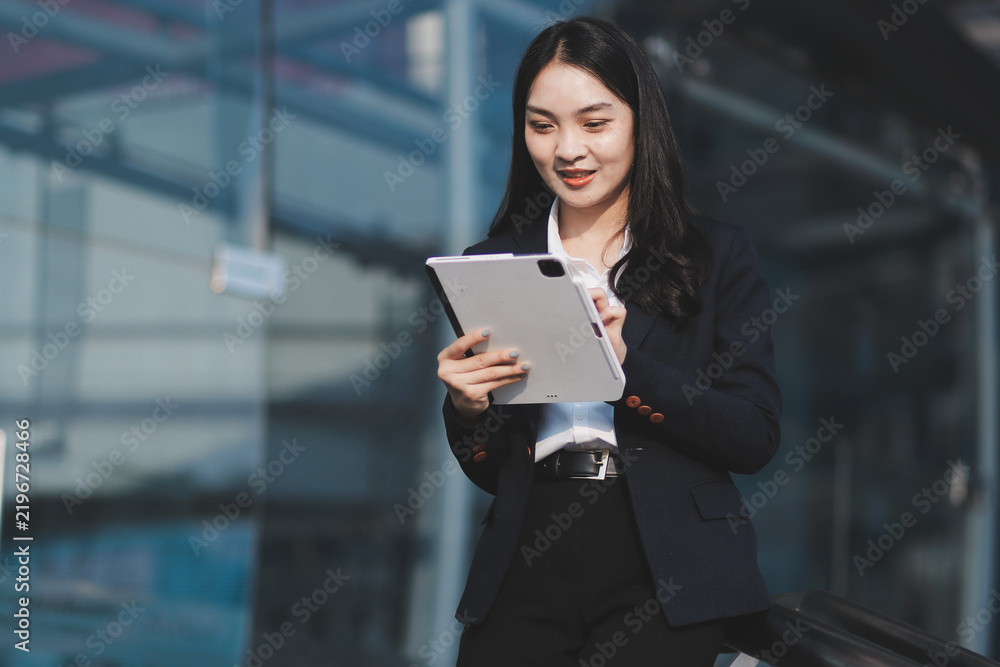 Obraz premium Young businesswoman smiling while working with digital tablet at modern office building