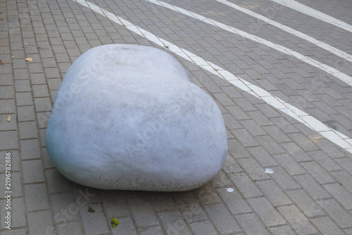 Smooth gray pebble shaped outdoor seat on geometric paving with diagonal white stripes