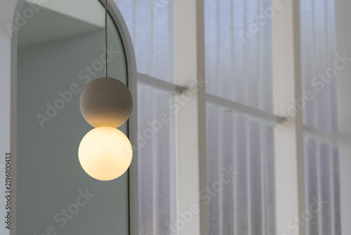 Minimalist hanging light fixture with warm glow near arched window