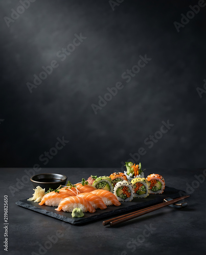 Photorealistic premium sushi advertising image of salmon nigiri and colorful vegetable rolls on a black slate plate, subtle chopsticks and a small soy dish, elegant charcoal background