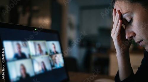 presbyopia woman stress fatigue concept. Woman stressed during virtual meeting with multiple participants on screen.