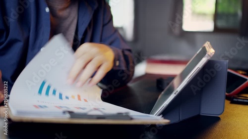 Businessman reviewing and flipping through financial performance report documents on a clipboard at his desk.